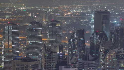 Jumeirah Lakes Towers district with many skyscrapers along Sheikh Zayed Road aerial night timelapse. photo