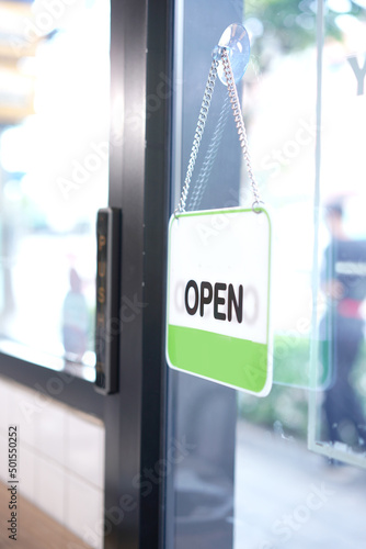 Open and closed flip sign in front of coffee shop and restaurant glass door. Wooden sign with wording of place's status OPEN.