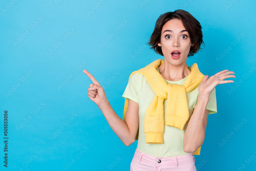 Photo of cute excited lady dressed yellow pullover pointing two fingers empty space isolated blue color background Photo of cute excited lady dressed yellow pullover pointing two fingers empty space isolated blue color background