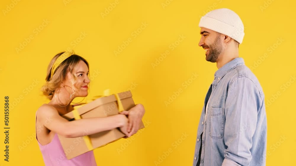 HD Young handsome giving big gift present box to young woman on yellow background. Amaized and surprised reaction. HD Young handsome giving big gift present box to young woman on yellow background. Amaized and surprised reaction.