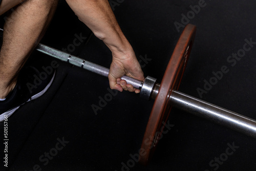 Unrecognizable Latin American man performing functional workouts executed at high intensity in the gym using a barbell with weights. Healthy Lifestyle Concept