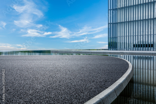 Photographie Asphalt road platform and glass wall building with sky cloud background