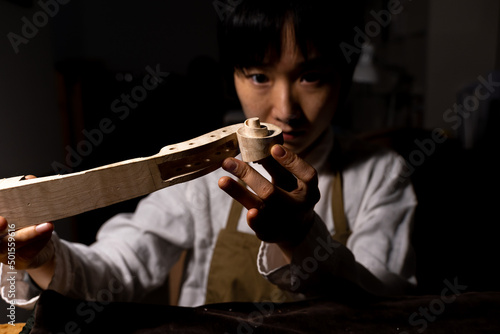 Obraz na płótnie young Chinese female violin maker working on the neck of the violin under constr