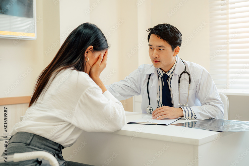 Asian male doctor in white medical uniform consult female patient on consultation. They Consult Digital Tablet Computer while Talking about Patient's Health. Asian male doctor in white medical uniform consult female patient on consultation. They Consult Digital Tablet Computer while Talking about Patient's Health.