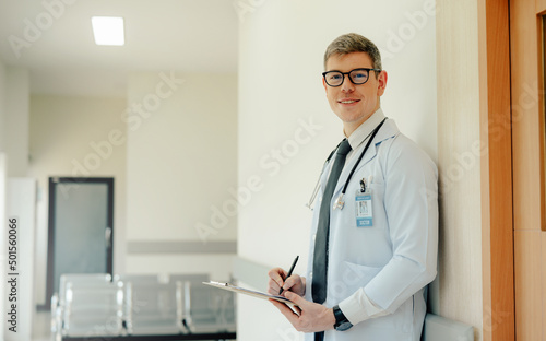 Portrait of Mature Male Doctor Wearing white Coat Standing in Hospital Corridor. Concept Of Medical Technology and Healthcare Business.