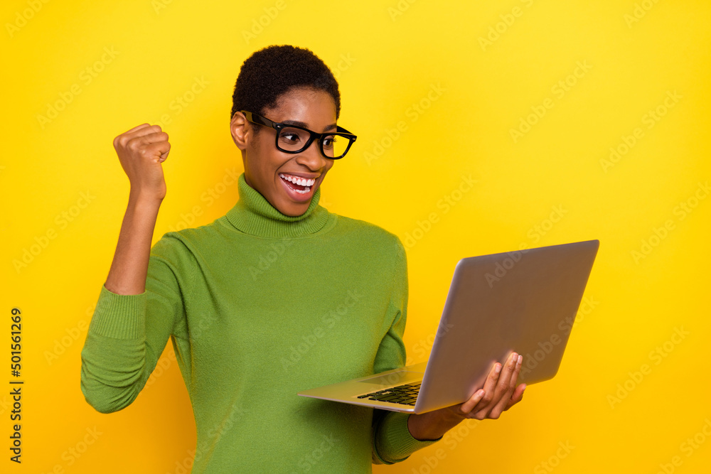 Photo of funny excited short hair lady dressed green turtleneck rising fist reading modern gadget isolated yellow color background