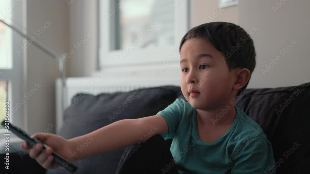 Little cute boy switch channels with remote control on TV at home Little cute boy switch channels with remote control on TV at home