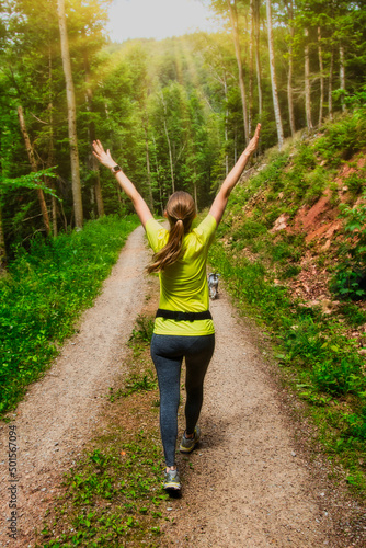 Girl Hiking in the Forest with a dog during sunset