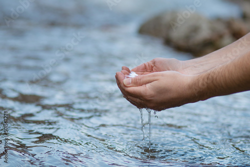 Hands scoop clean water from the stream. Drink from the river. © Andrii Zastrozhnov