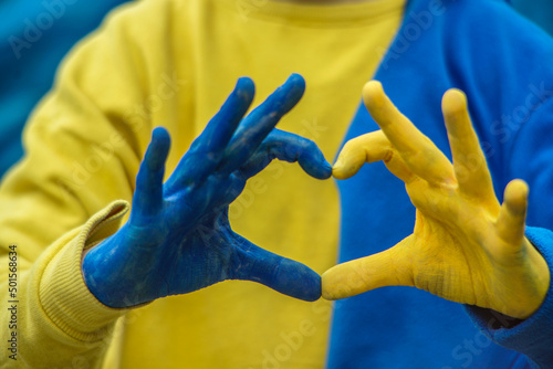 hands on a white background in the shape of a heart painted in yellow and blue Ukrainian flag. Russia's invasion of Ukraine, a request for help to the world community. Children ask for peace. Stop war