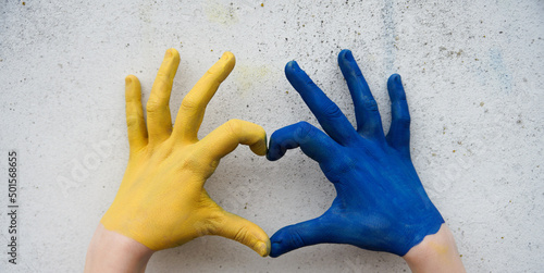 hands on a white background in the shape of a heart painted in yellow and blue Ukrainian flag. Russia's invasion of Ukraine, a request for help to the world community. Children ask for peace. Stop war