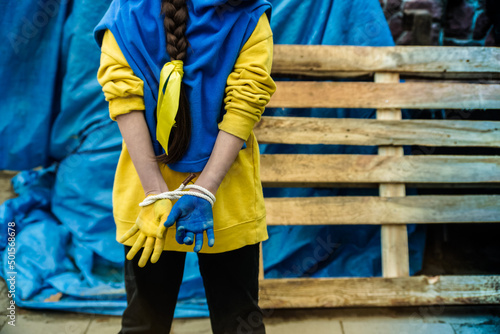 The child's bound hands are painted in the yellow and blue color of the Ukrainian flag. Russia's invasion of Ukraine, a request for help to the world community. Children ask for peace. Stop the war. 