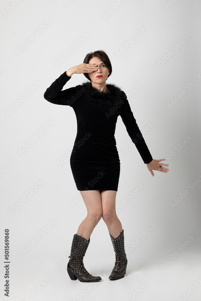 Beautiful woman standing on white background with sexy and elegant black dress, she covers one eye with her right hand Beautiful woman standing on white background with sexy and elegant black dress, she covers one eye with her right hand