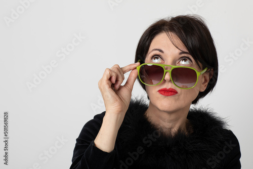 Portrait of brunette woman with green sunglasses looking up asking herself a lot of questions photo