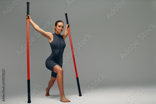 beautiful girl in sports uniform is training kung fu in the studio, fighter athlete, practicing martial arts with a stick