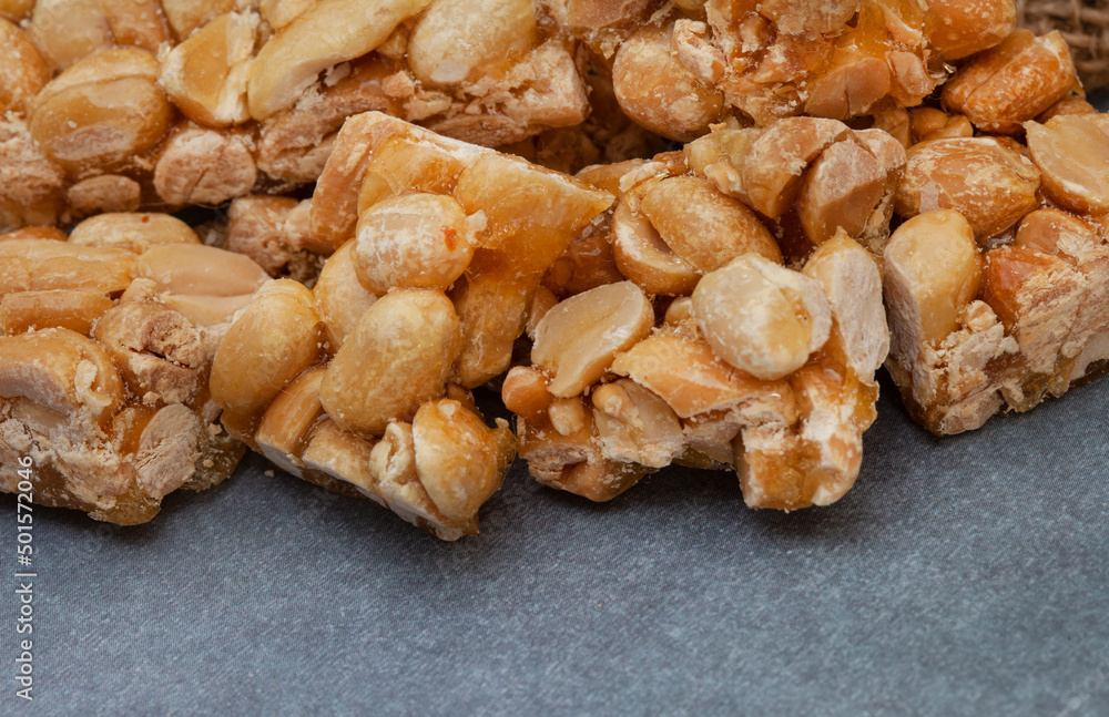 Peanut brittle, an old school sweet favorite, cut into small bars on rustic type surface with copy space Peanut brittle, an old school sweet favorite, cut into small bars on rustic type surface with copy space