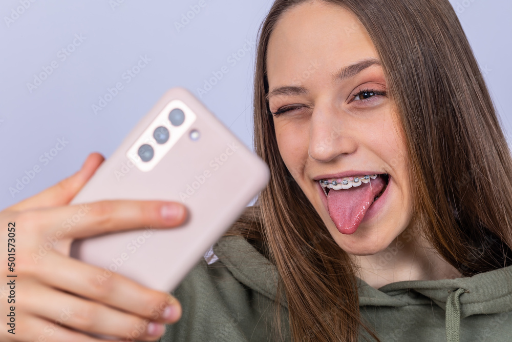 Young female laughing with tongue. Gray background. Young female laughing with tongue. Gray background.