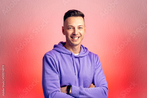 Smiling young good looking man standing against red gradient background