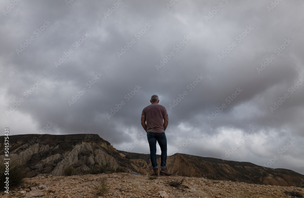 Rear view of adult man on oasis of desert against mountain and sky. Almeria, Spain