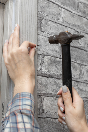 woman hammering a nail holding a hammer in her hand photo