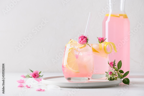 Pink rose cocktails, drinks or lemonade with rose flowers and lemon on white sunny background. Close up. Copy space.