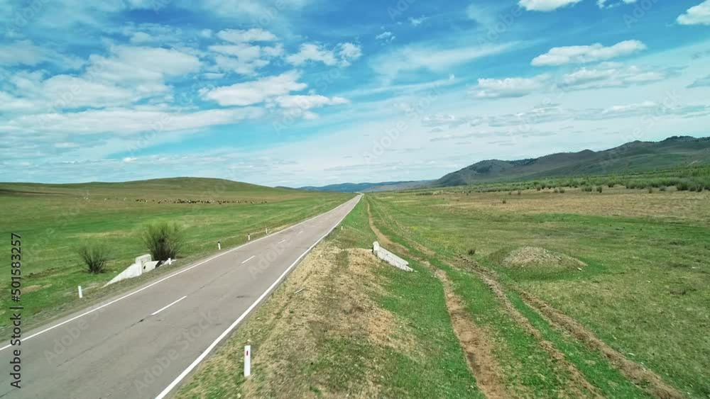 Aerial view of an asphalt road through the rural countryside area, road between green meadows. Aerial view of an asphalt road through the rural countryside area, road between green meadows.