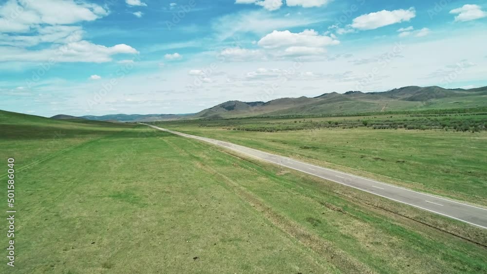 Aerial view of an asphalt road through the rural countryside area, road between green meadows. Aerial view of an asphalt road through the rural countryside area, road between green meadows.