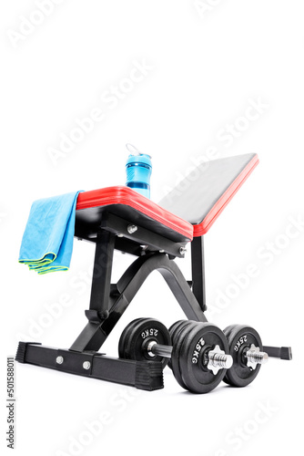 Dumbbells beneath a workout bench with towel and water bottle