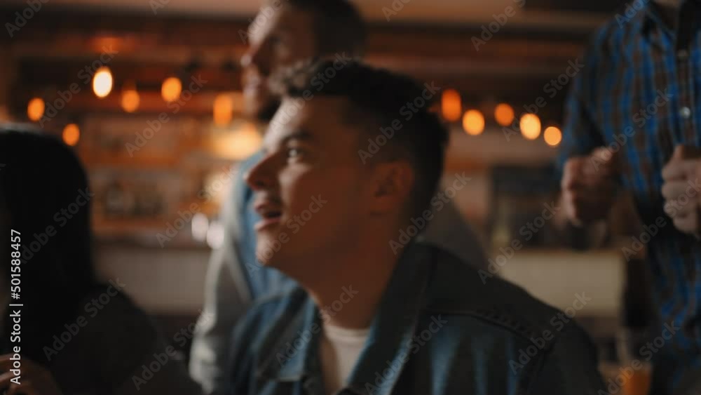 Close-up of a group of fans of men and women sitting together in a bar and watching a broadcast on TV, enjoying a goal scored, shouting and hugging. World Cup in football Close-up of a group of fans of men and women sitting together in a bar and watching a broadcast on TV, enjoying a goal scored, shouting and hugging. World Cup in football