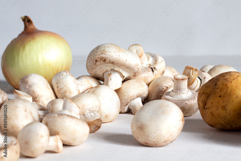A bunch of champignons, potatoes and onions on the table. A bunch of champignons, potatoes and onions on the table.