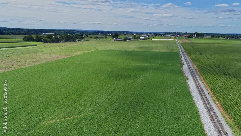 An Aerial 180 Degree View of Rich Farmlands and Corn Fields Along a Single Railroad Track on a Sunny Summer Day An Aerial 180 Degree View of Rich Farmlands and Corn Fields Along a Single Railroad Track on a Sunny Summer Day