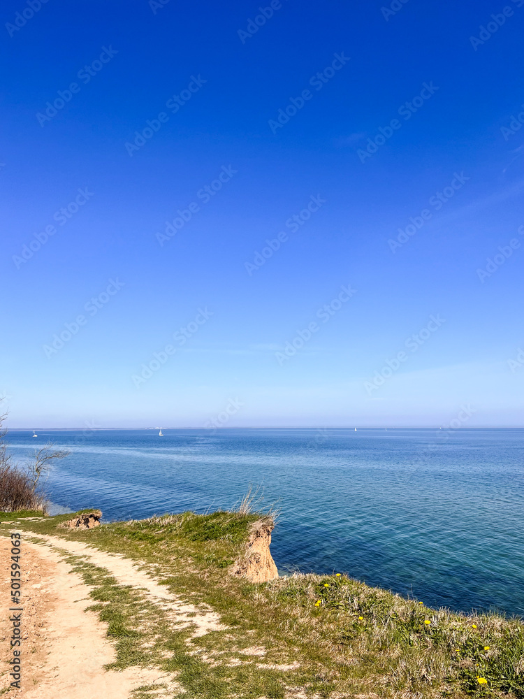 Landscape of blue Baltic sea with white sand and cloudy sky