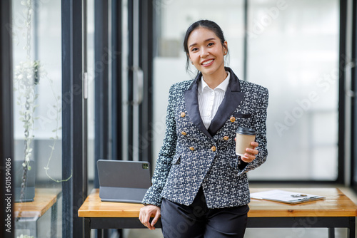 Charming Young Asian businesswoman standing in the office. Looking at camera.