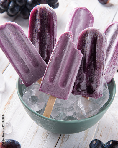 .Grape popsicles in bowl with ice cubes. photo