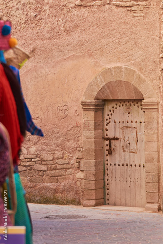 Old traditional moroccan door and a display of multi-cloured scarves in Essaouira Morocco © Cristina