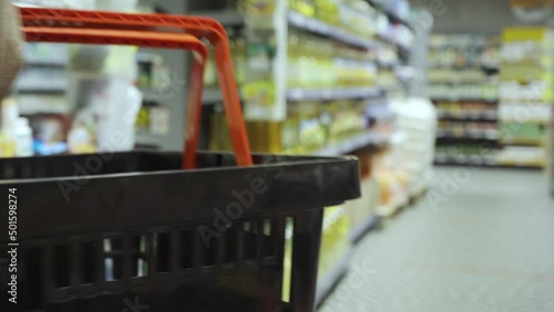 Wallpaper Mural Young woman walking down the aisles of a supermarket with a basket of groceries Torontodigital.ca