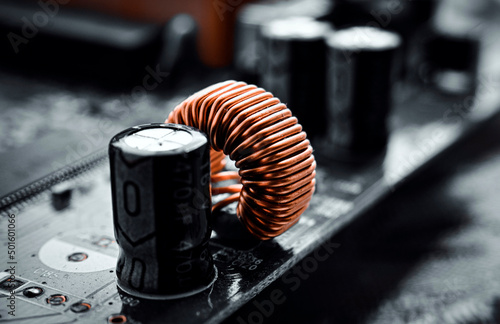 Printed circuit board with toroidal coil and black capacitors. selective focus photo