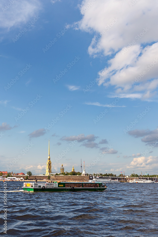 view of the Neva River in St. Petersburg and tourist ships against the backdrop of the ancient Peter and Paul Fortress and the blue sky