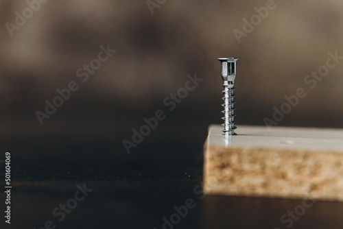 a silver screw screwed into wooden plank