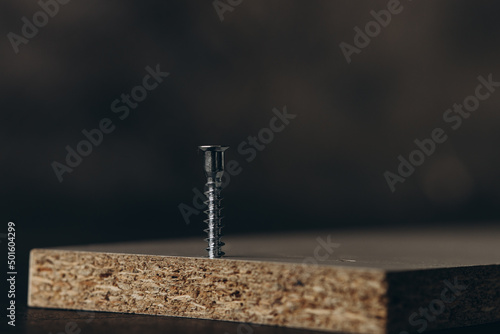Closeup of screw being screwed into a wooden plank - macro shoot