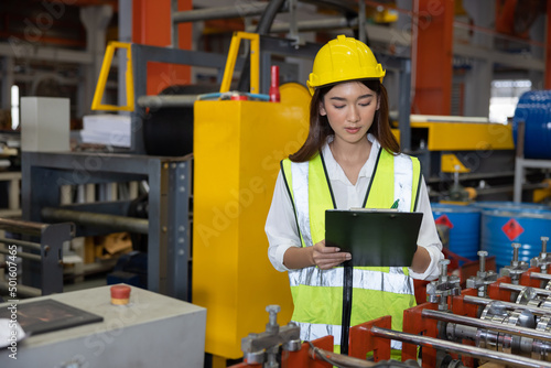 Female Factory Inspector Checking the Machine While Jotted Down the Note on a Cl Fototapet