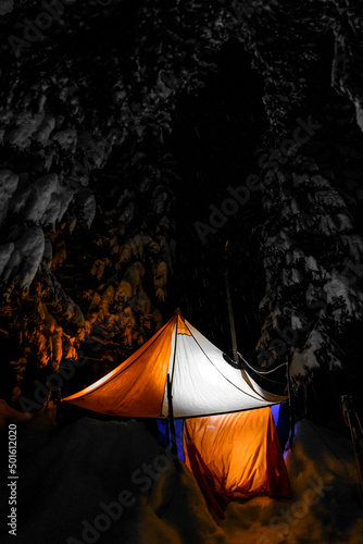 Mountain winter night landscape of orange tent with turned on light indide. photo