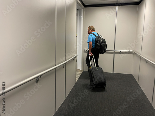 A man walking in the jetway to board an airplane at an airport. photo