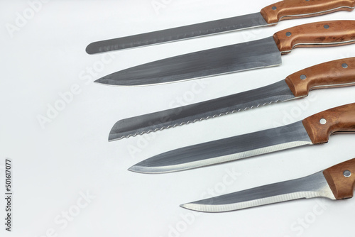 As assortment of kitchen knives flat laid on a neutral background. Collection of various kitchen knives. Chef, restaurant or kitchen concept.