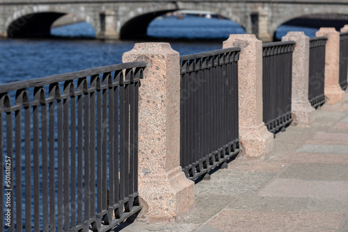 Carta da parati Fence on the embankment of the Fontanka River, granite pillars with a forged fence against the background of the spans of the bridge, in the city of St