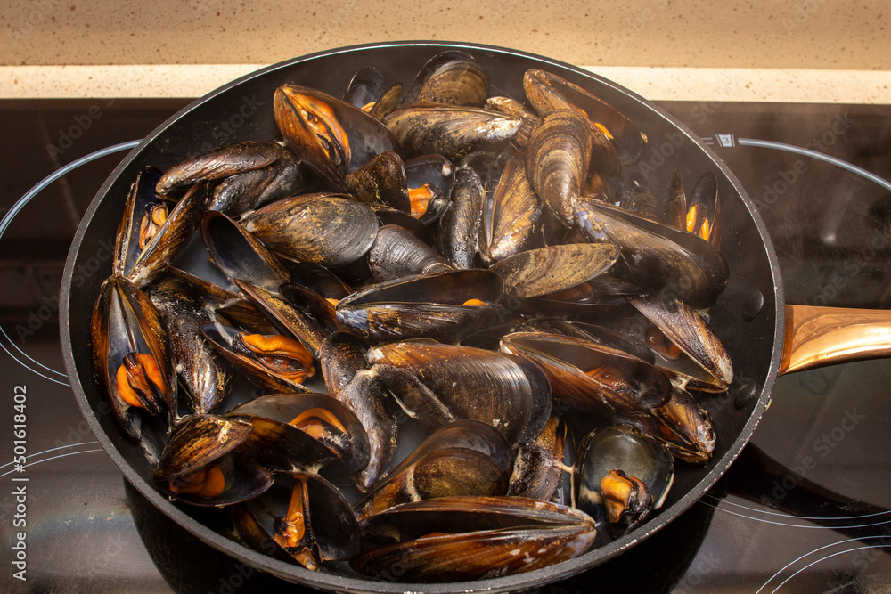 Cooking mussels in a pan. Mussels are perfect in endless fish recipes, but the simplest and most traditional in Galicia are steamed mussels. Cooking mussels in a pan. Mussels are perfect in endless fish recipes, but the simplest and most traditional in Galicia are steamed mussels.