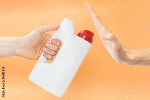 Man rejecting to take a white jerry can with red cap on an orange background. Machine. Plastic. Washing. Canister. Storage. Dishwashing. Equipment. Clean. Housework. Kitchen. Modern. Set. Handle photo