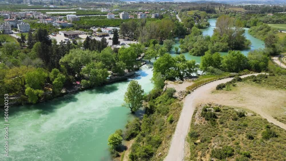 A beautiful waterfall that flows into the river, among green trees, mountains and amazing fields A beautiful waterfall that flows into the river, among green trees, mountains and amazing fields