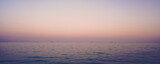 Beautiful panoramic view to calm sea surface with cargo tanks on horizon line at sunset