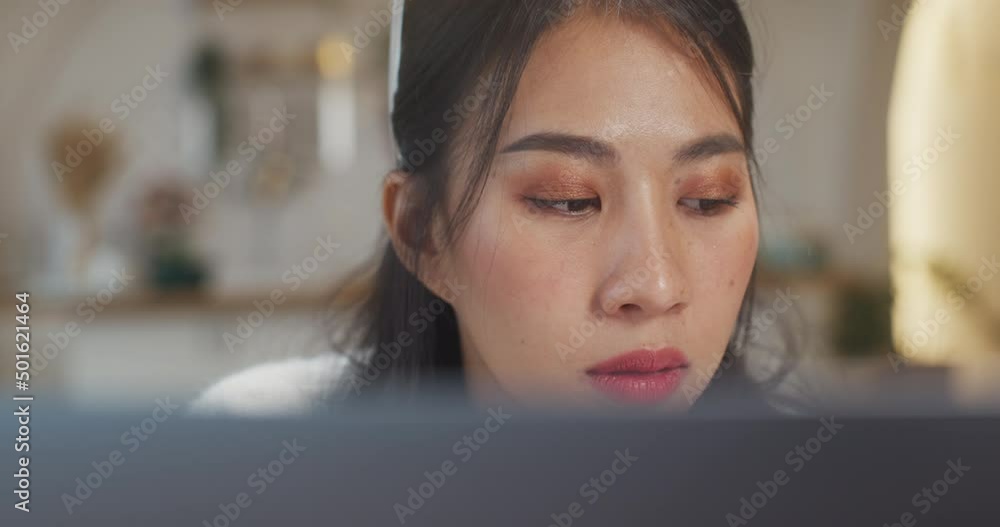 Young asia lady freelance focus on presentation work in laptop for account and finance project for remote meeting with company in kitchen at house. Girl student learn online at home. Close up shot. Young asia lady freelance focus on presentation work in laptop for account and finance project for remote meeting with company in kitchen at house. Girl student learn online at home. Close up shot.